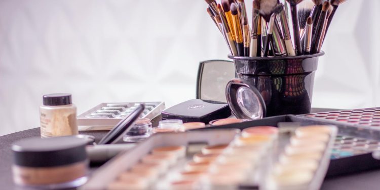 Close-up of a professional makeup brush set and cosmetics on a table for beauty use.