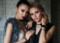 Elegant portrait of two fashionable women showcasing modern style and beauty against a textured backdrop.