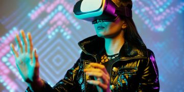 Woman using VR headset with interactive neon lights indoors, embracing digital innovation.
